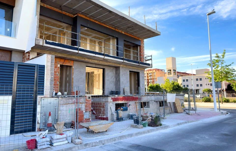 Chantier de construction extérieur avec contremaître en casque blanc et chemise à carreaux consultant des plans ou documents